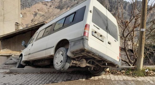Buzlu yolda kayan minibüs askıda kaldı