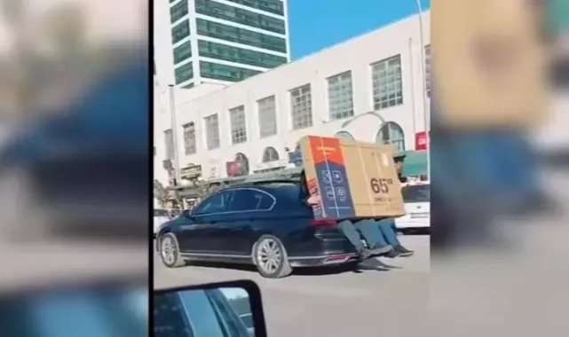 Yeni alınan televizyonu otomobilin bagajına oturan 2 kişi taşıdı