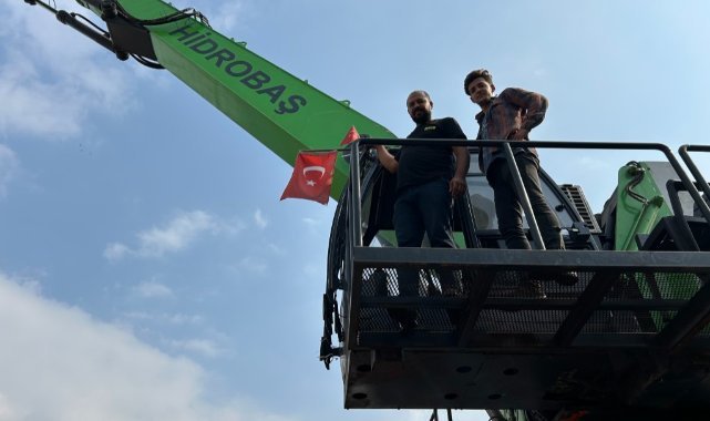Hurda yığını içerisindeki Türk bayrağını elleriyle çıkararak iş makinesine astı
